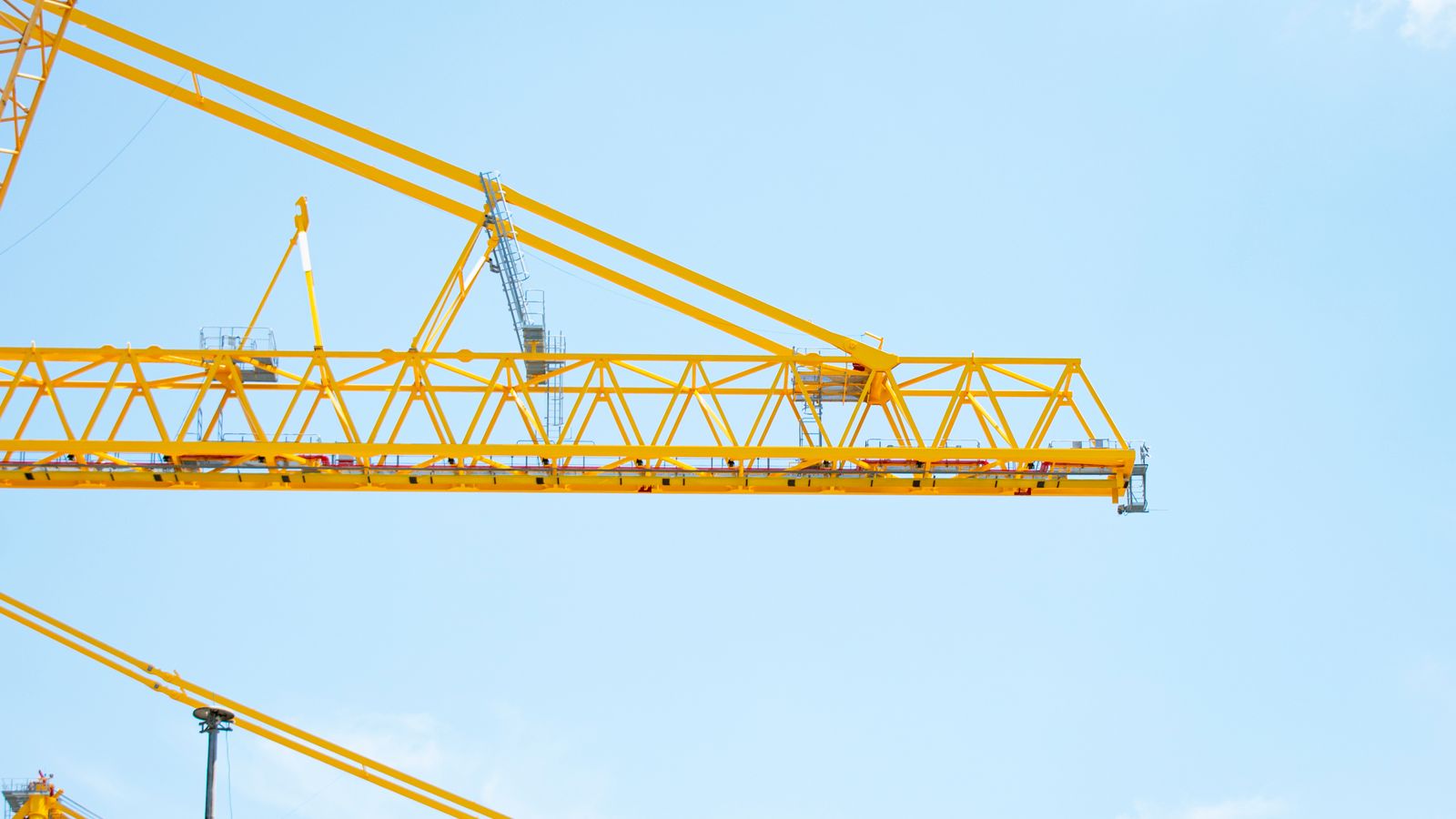 青空に伸びる黄色いタワークレーンのある建設現場。建設株の高配当バリュー投資の安定性を象徴するイメージ。