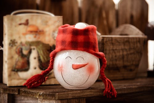Стеклянная фигурка снеговика на коричневой деревянной поверхности
