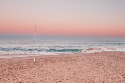 Fishing Rod on Beach at Dusk under Clear Sky