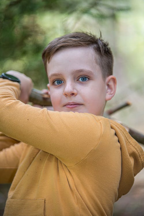 Boy in Yellow Sweatshirt Holding Wooden Stick