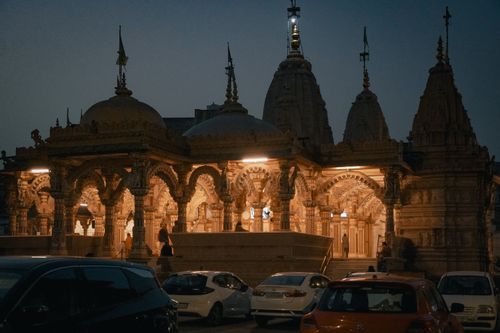 Free A captivating evening view of Swaminarayan Temple in Ahmedabad with illuminated architecture and parked cars. Stock Photo