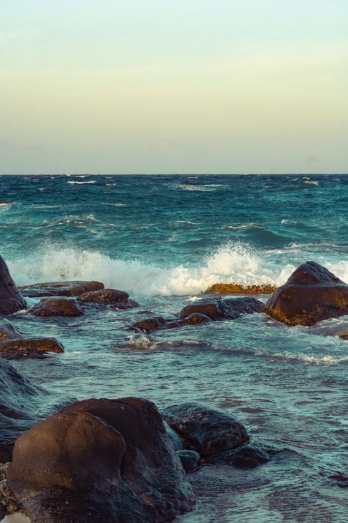 Free Scenic view of rocks and waves by the sea under a clear sky. Stock Photo