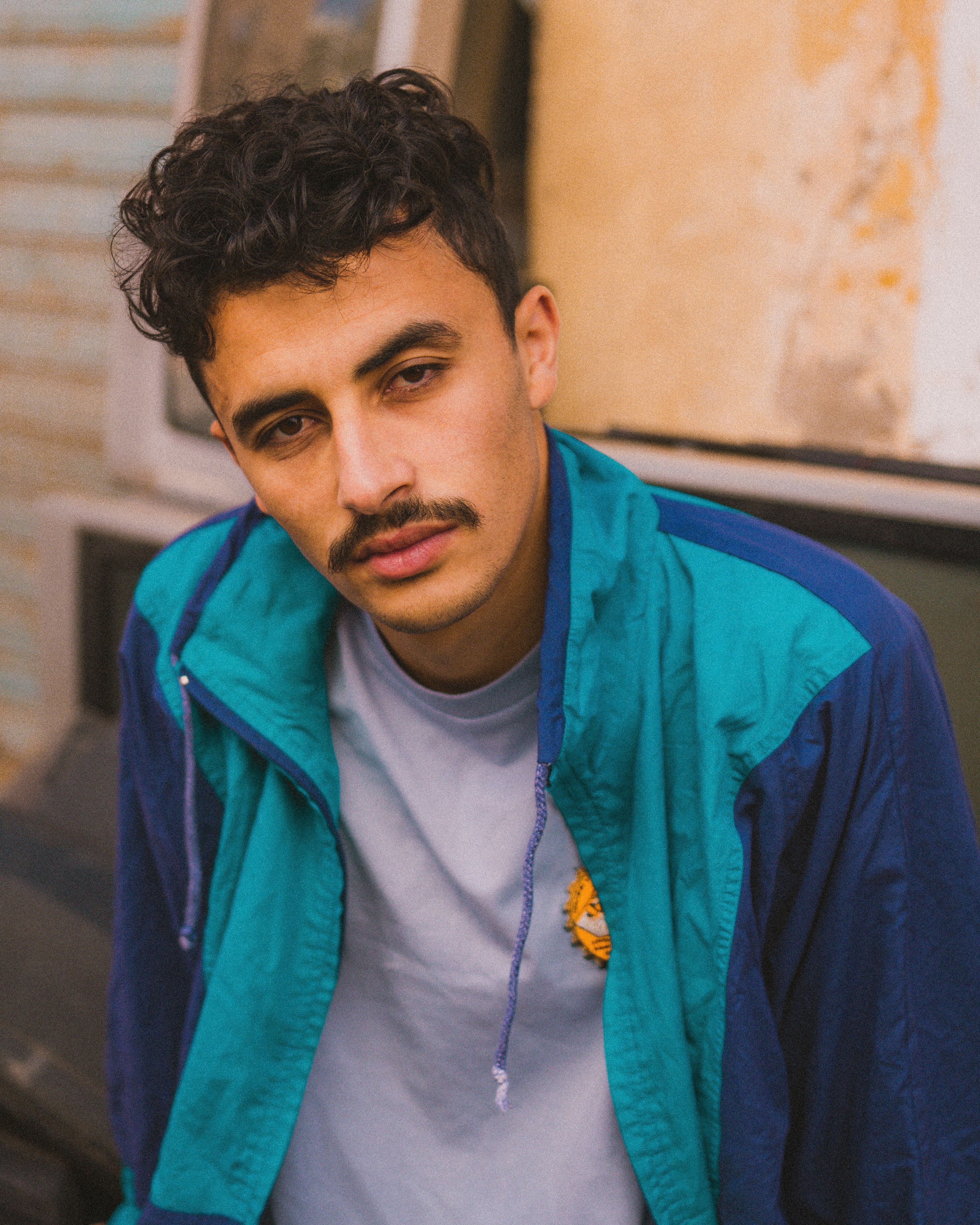 A man in a casual outfit poses outdoors with a relaxed expression.