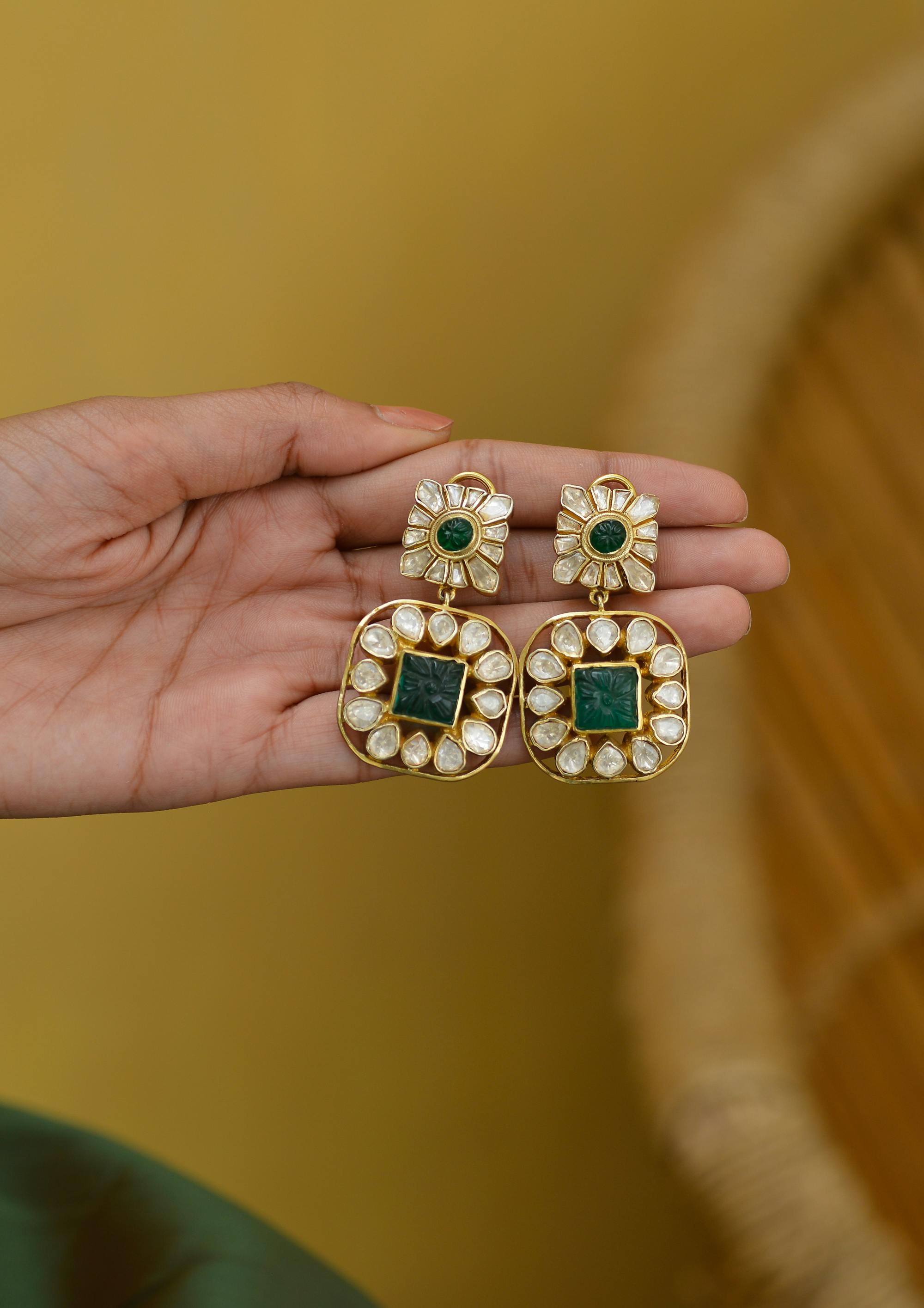 earrings with emeralds and diamond in woman hand