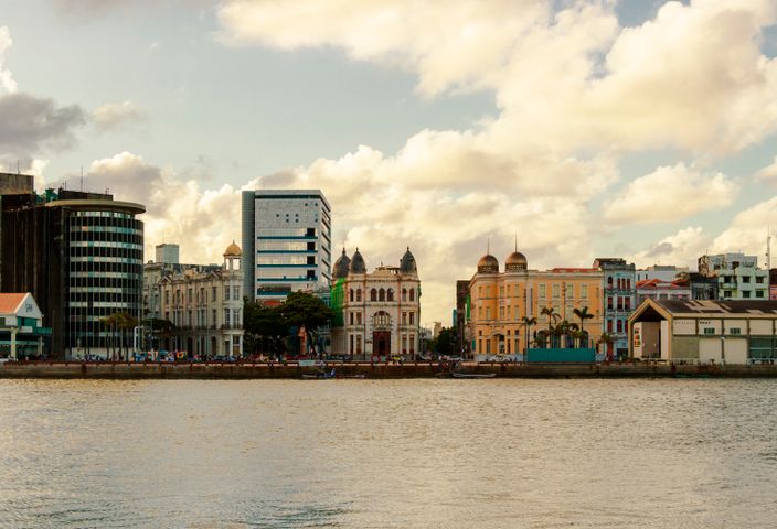 Scenic view of Recife's waterfront architecture showcasing historic and modern buildings under a partly cloudy sky.