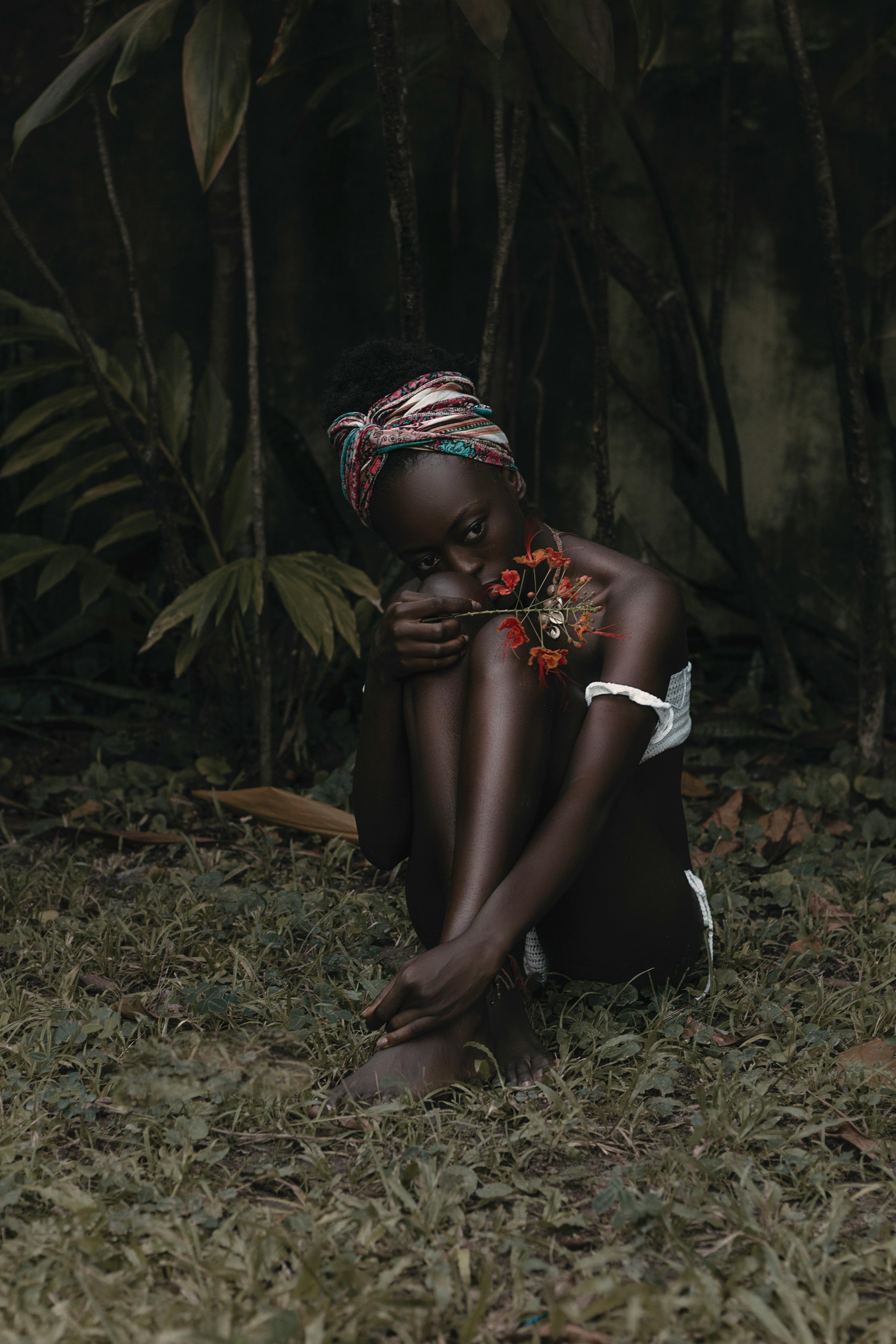Elegant outdoor portrait capturing a woman in a forest setting with vibrant flowers.