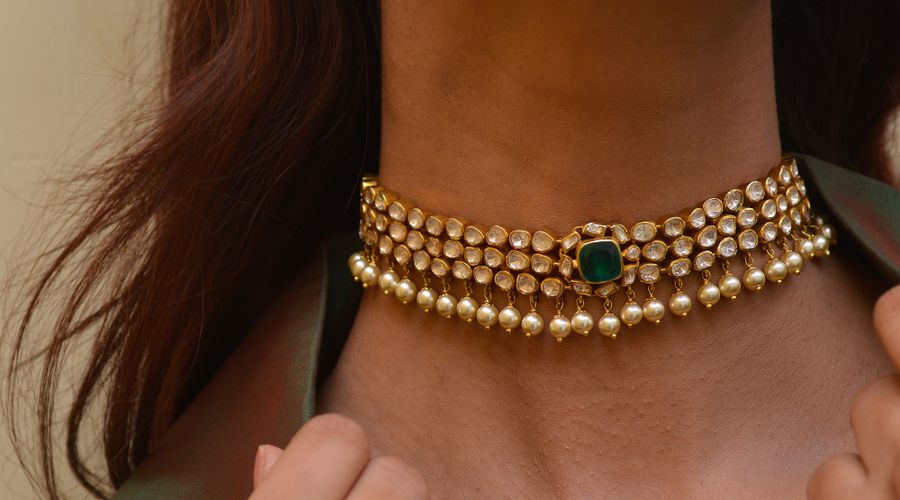 Collier doré et boucle d'oreille assortie portés par une femme