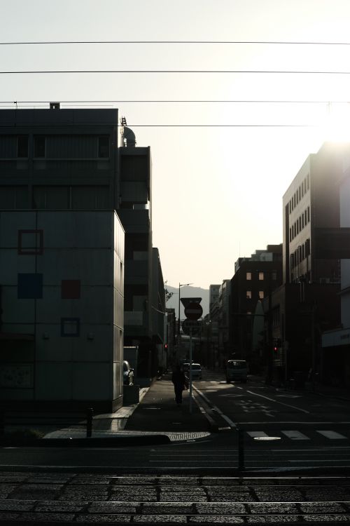 Free City street scene with silhouetted buildings and warm sunlight creating a dramatic urban atmosphere. Stock Photo