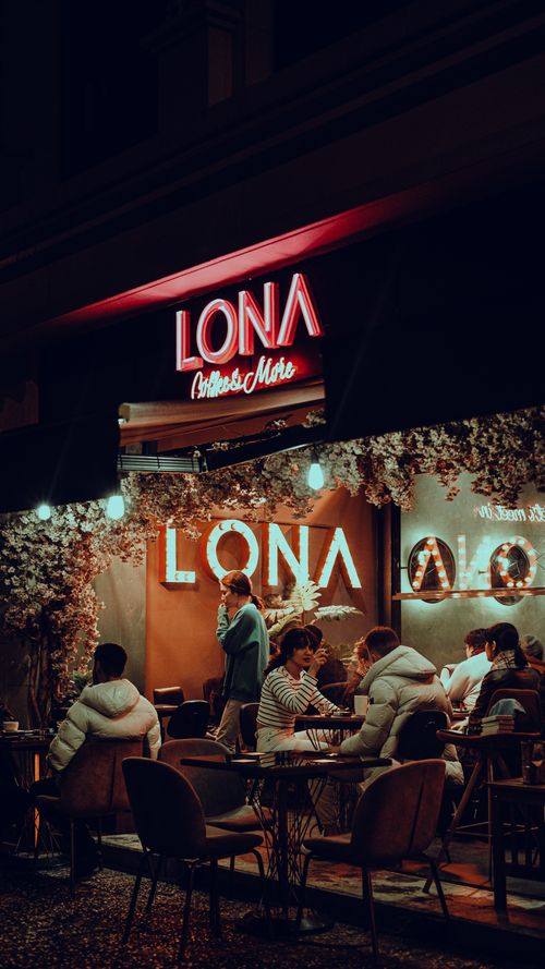 Free Cozy evening at LONA Coffee & More, featuring neon signs and people enjoying leisure time. Stock Photo