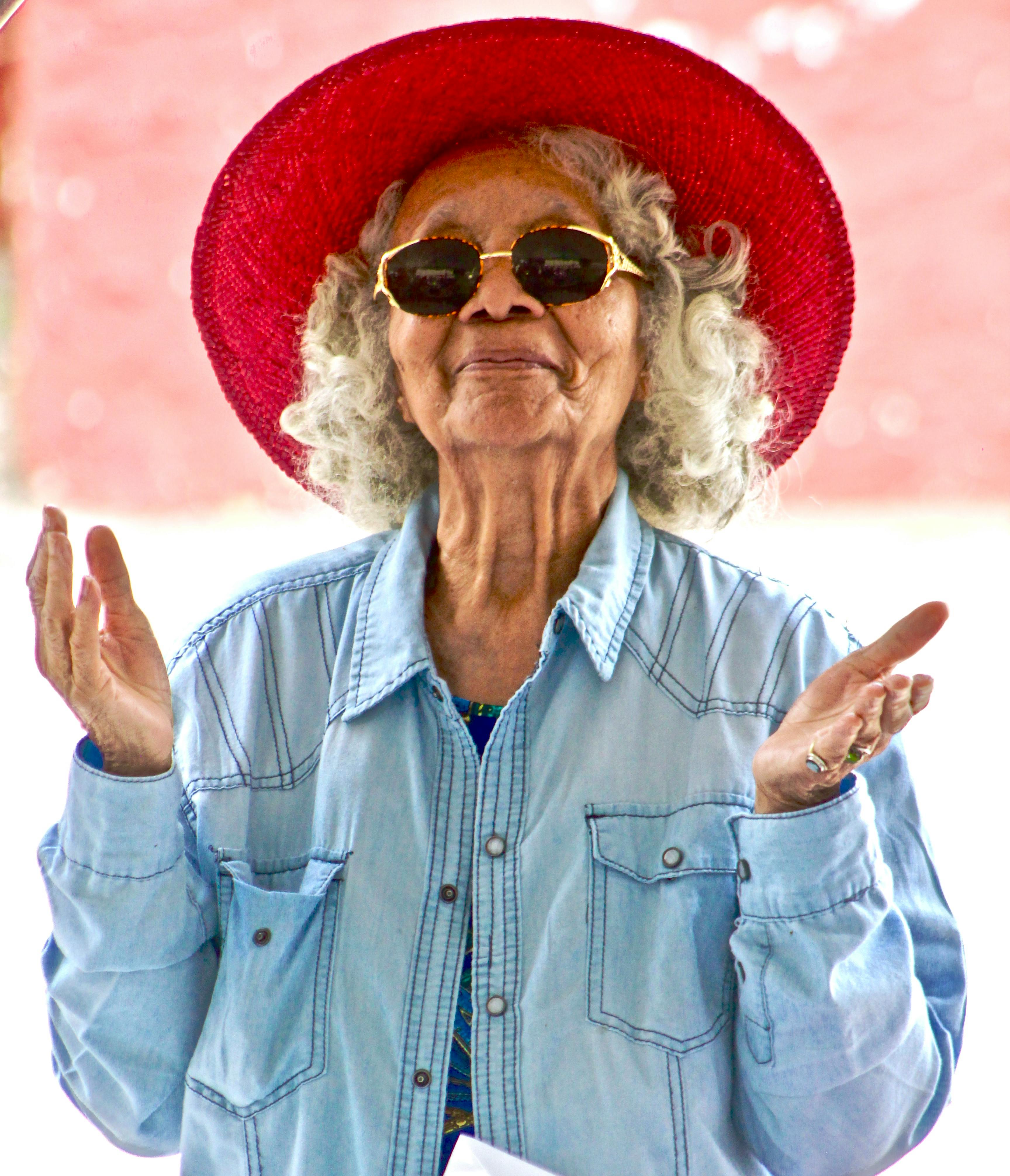 An old woman wearing a red hat and sunglasses. | Photo: Pexels