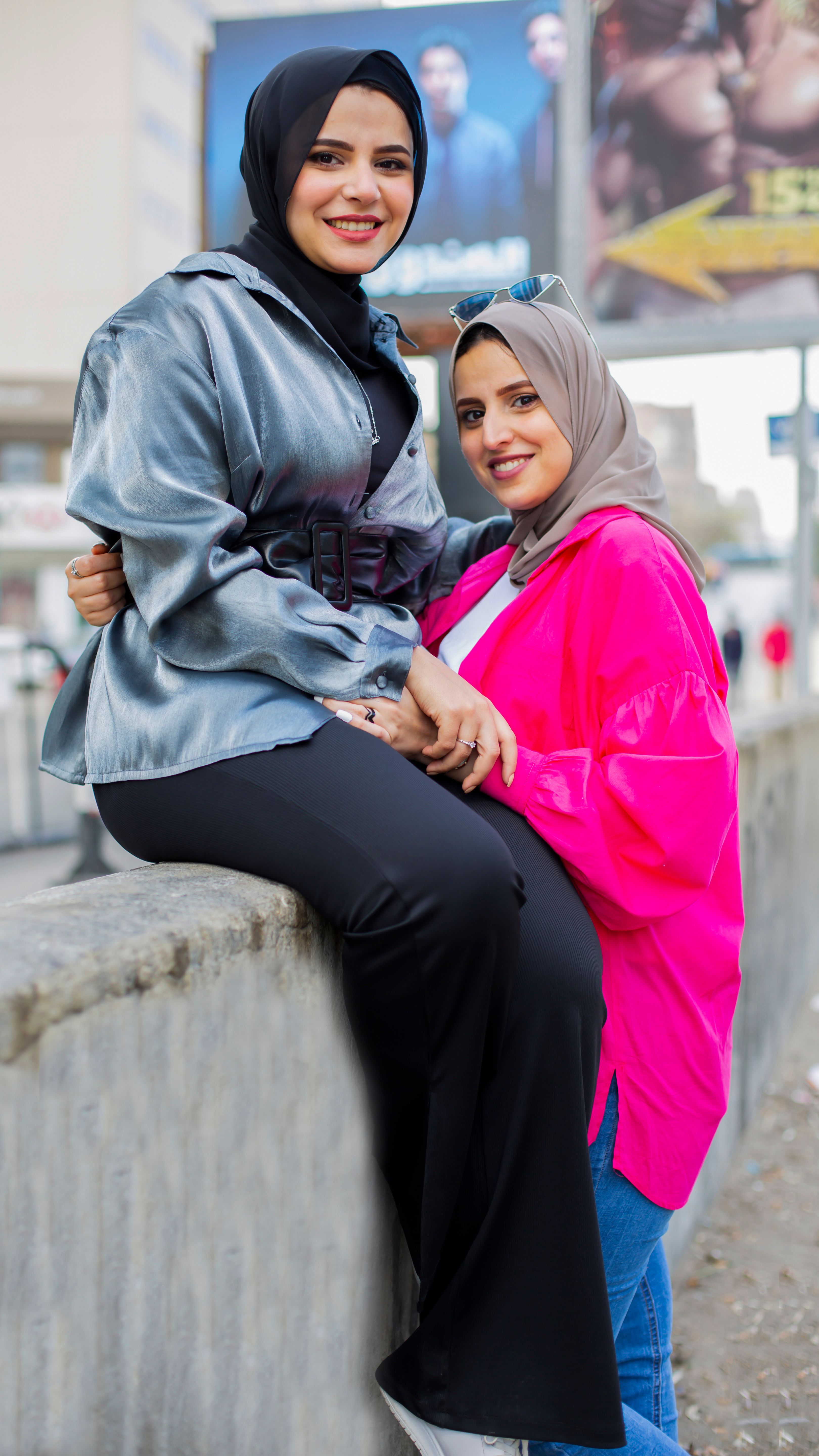 Two stylish women in hijabs enjoying a day out, showcasing urban fashion and friendship.