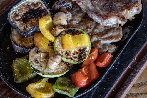Free Tasty grilled vegetables and beef steak served sizzling on a hot plate, perfect for a hearty meal. Stock Photo