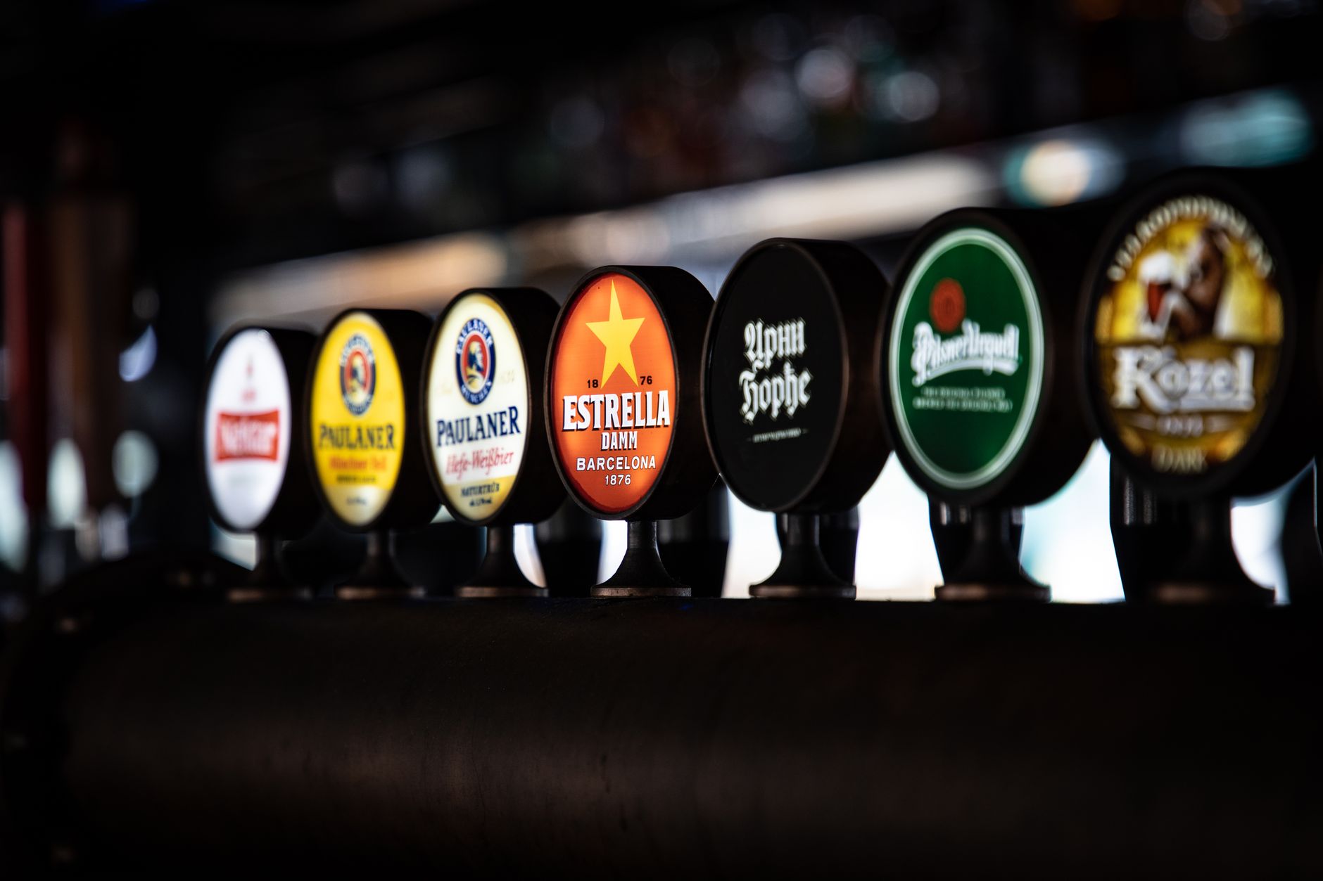 A variety of beer taps featuring distinct brand labels in a row at a bar setting.