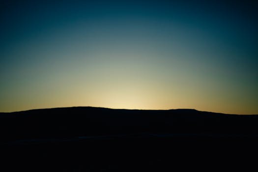 Peaceful twilight scene with a silhouette of hills. Perfect for serene and calming visual themes.