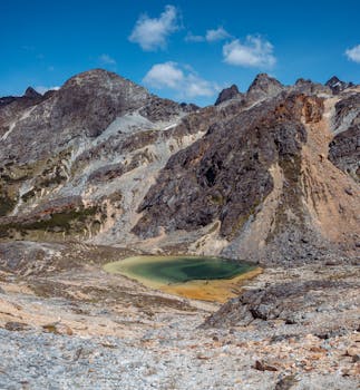 Stunning rocky mountains and a serene lake under a bright blue sky.
