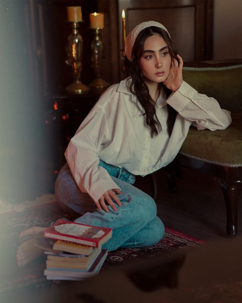 Free Elegant woman in white shirt posing on floor with books and candles. Stock Photo