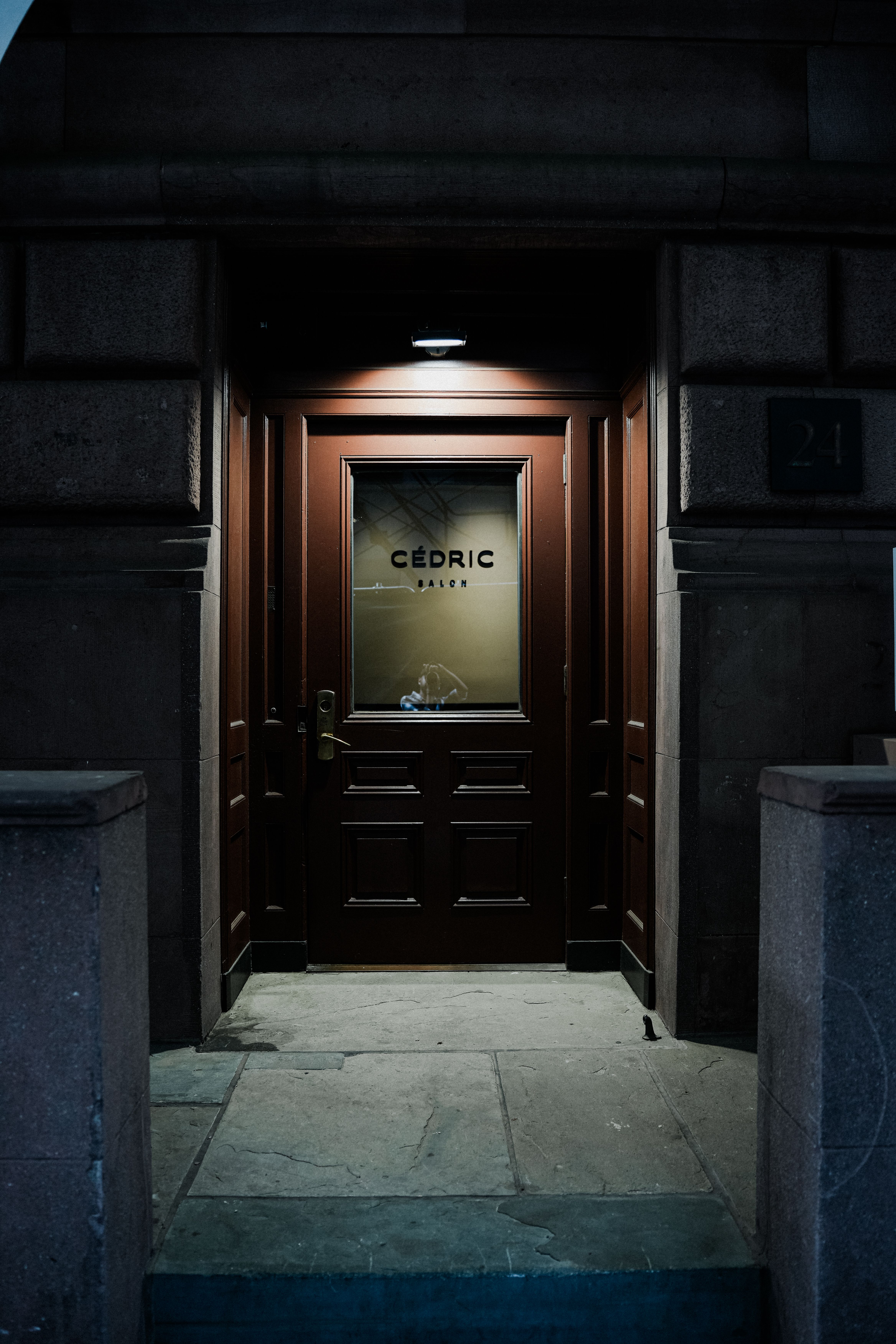 A beautifully illuminated wooden door with Cédric signage, exuding elegance and mystery at night.