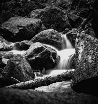 A serene black and white waterfall cascading over rocks in a natural setting.