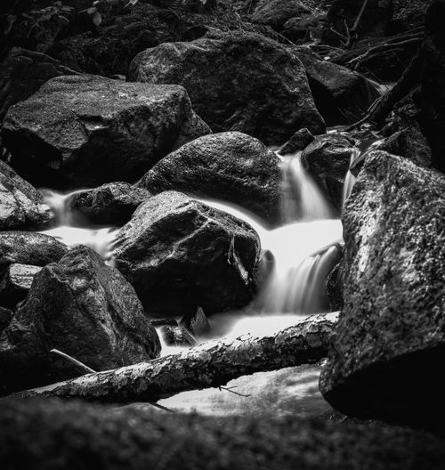 Free A serene black and white waterfall cascading over rocks in a natural setting. Stock Photo