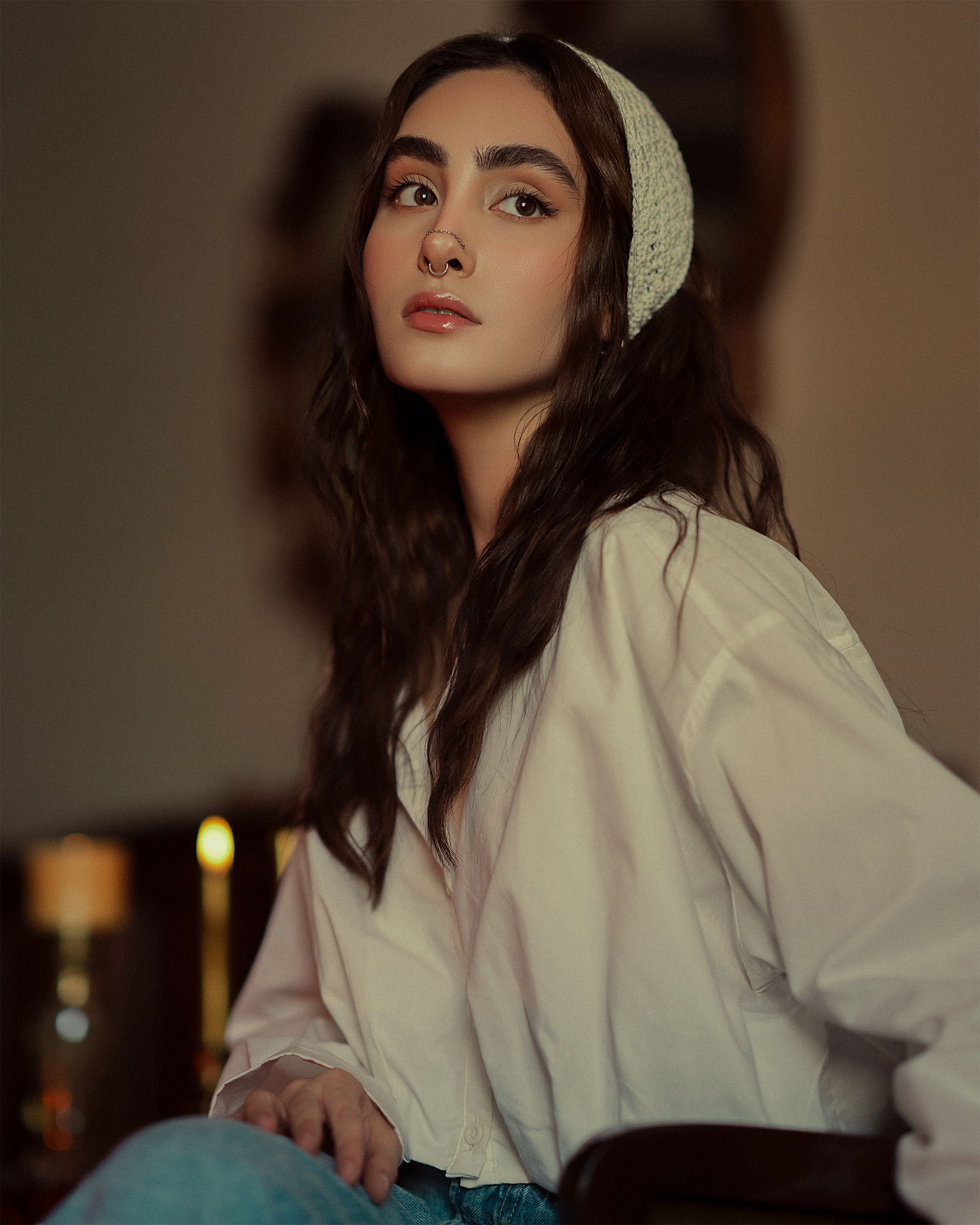 Elegant portrait of a woman with long hair wearing a white shirt indoors.