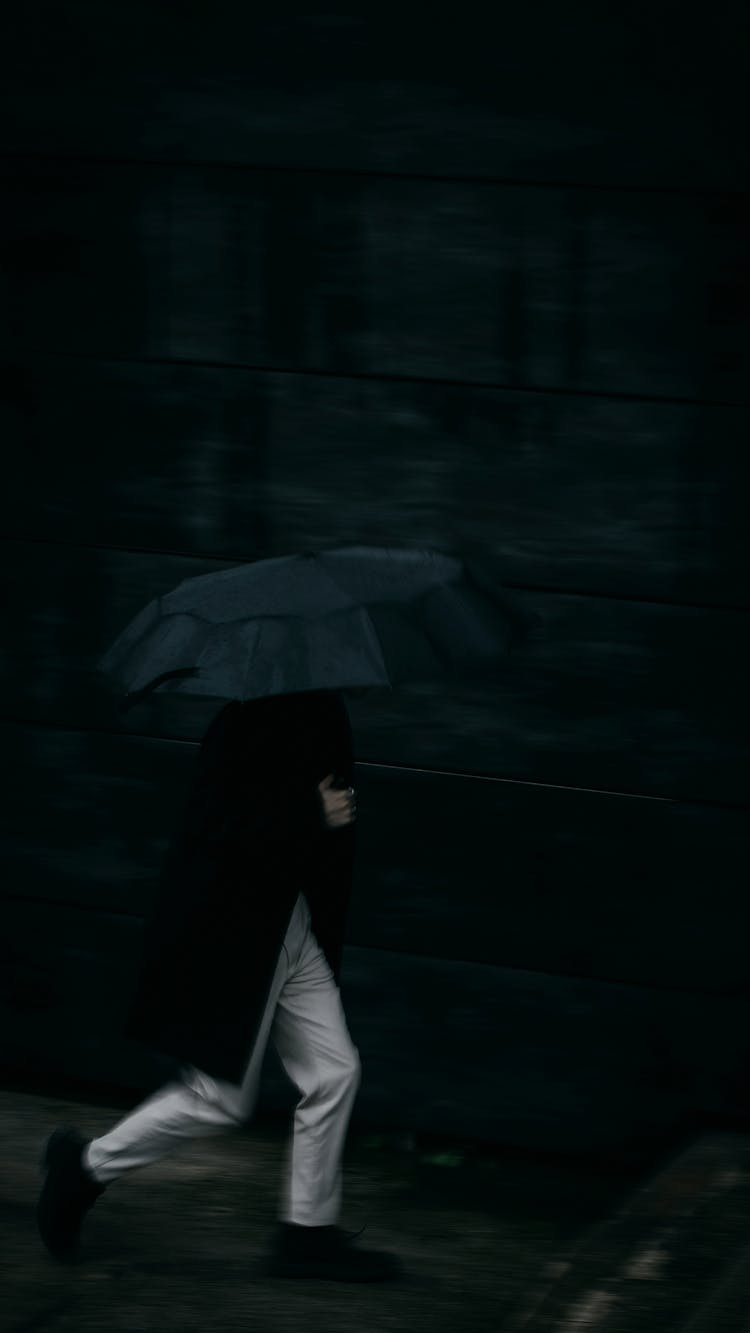 Man Running Under Umbrella In Rain