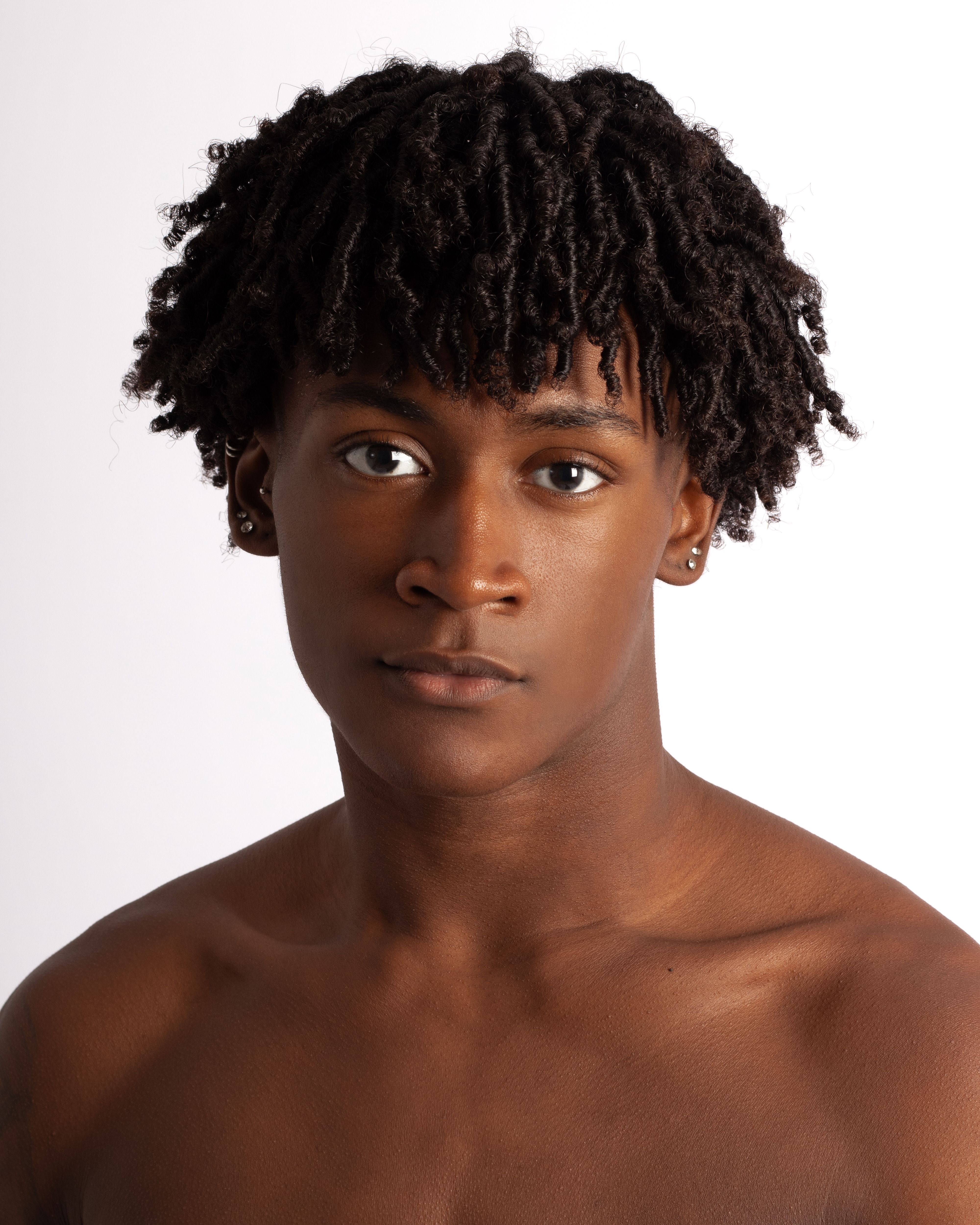Studio portrait of an adult man with curly hair against a white background.