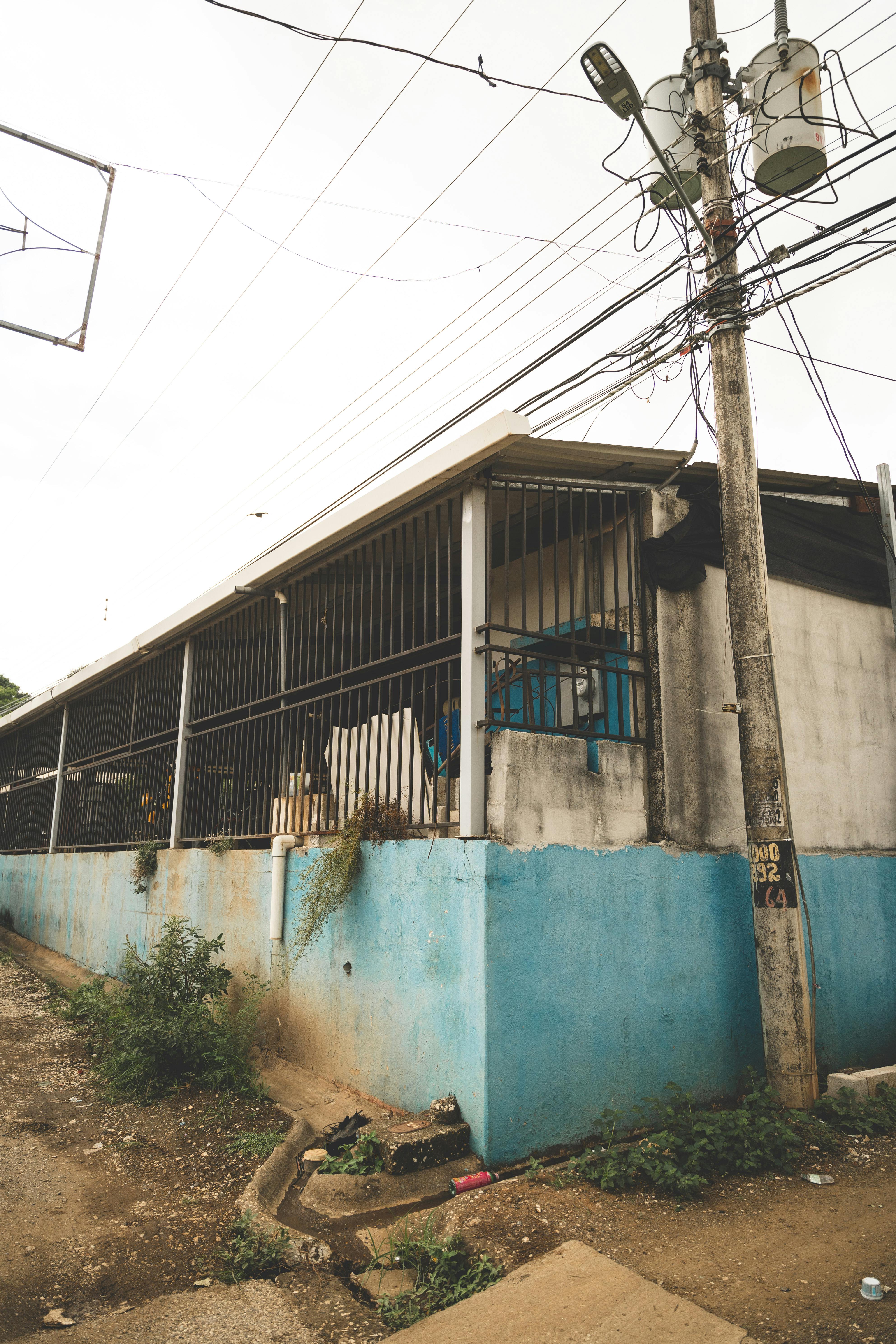 Free A street corner featuring a building with a power line and utility pole, under cloudy skies. Stock Photo