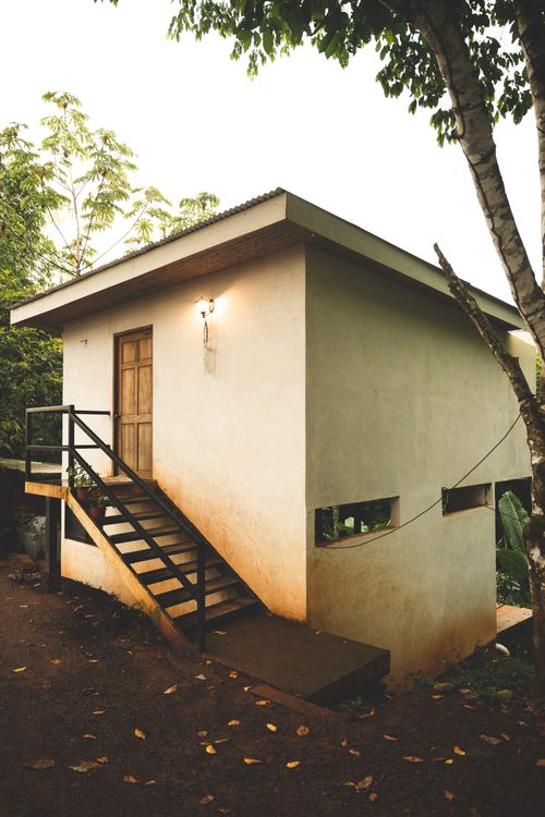 Free Rustic rural house with stairs, nestled among trees, offering a serene escape in nature. Stock Photo