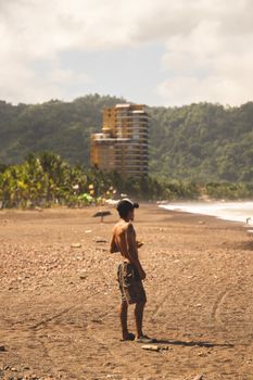 A man enjoys a serene beach with jungle backdrop, perfect for travel inspiration.