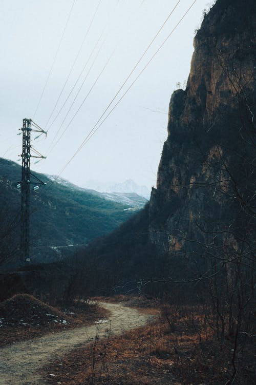 Footpath under Power Lines near Rock Formation in Valley
