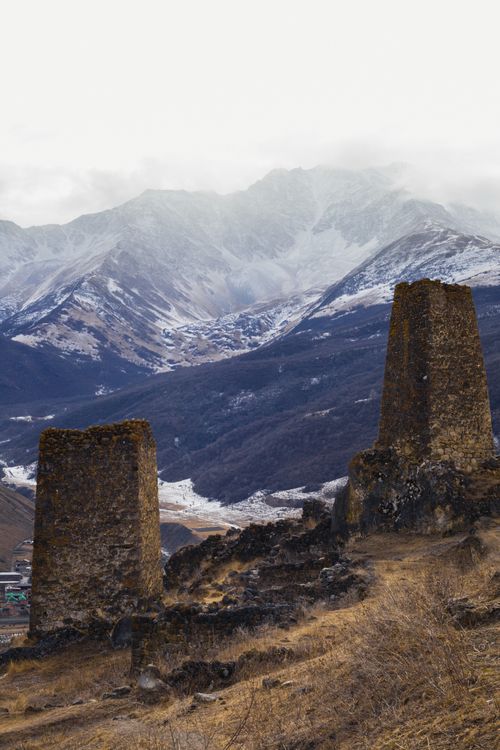Free Ancient stone towers overlooking a snow-capped mountain range, surrounded by fog. Stock Photo