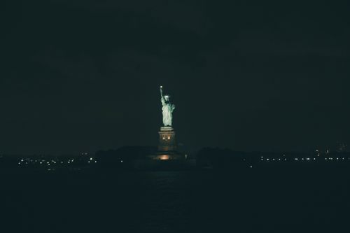 Free The Statue of Liberty glowing against a dark night sky in New York City. Stock Photo