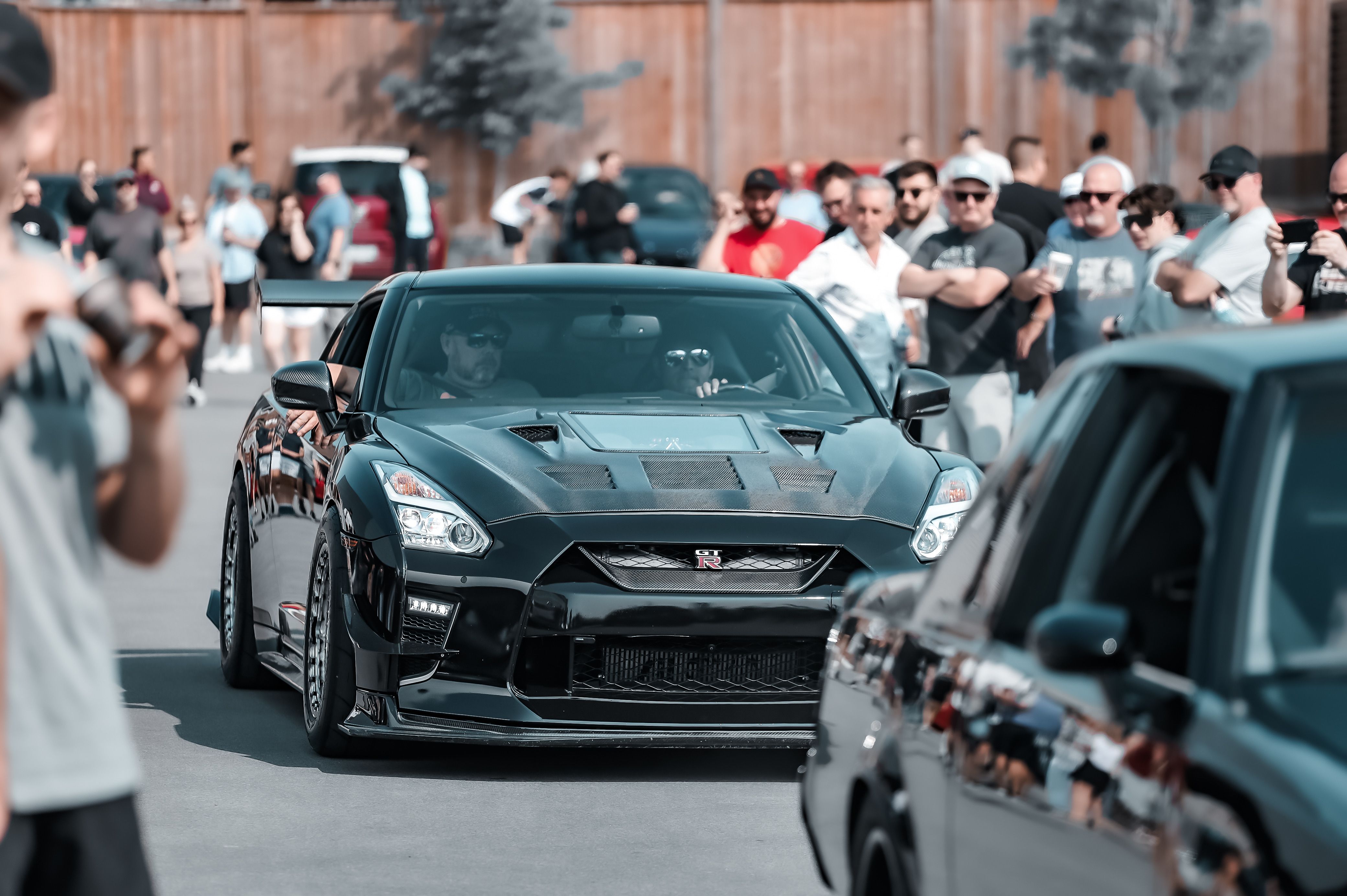 A thrilling street parade showcasing sleek cars draws a lively crowd in the city.