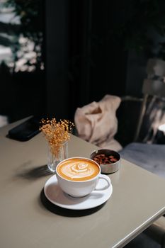 A creamy latte with beautiful froth art served on a table in a cozy cafe setting.