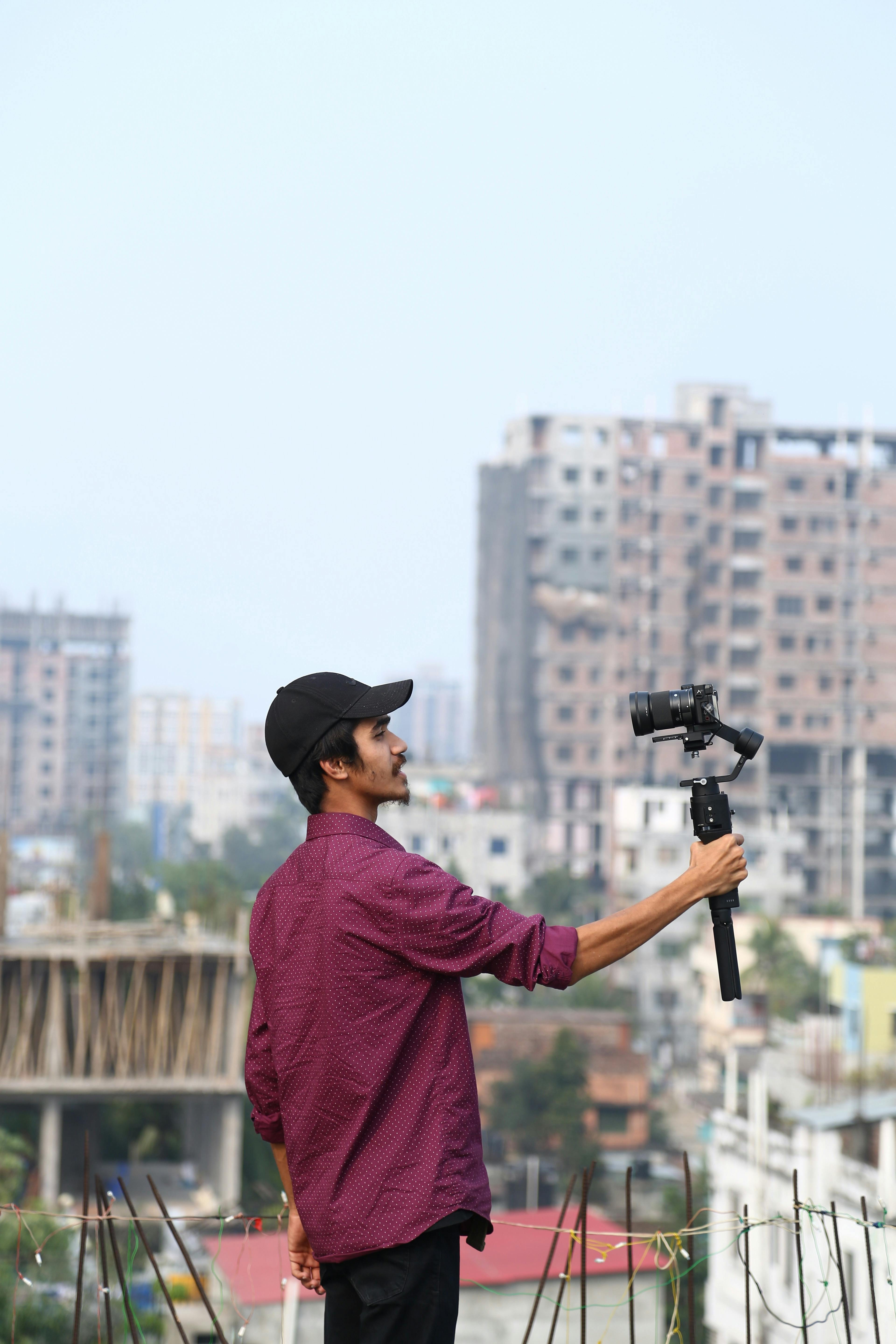 A man in Mymensingh taking a selfie with a camera amidst an urban backdrop.