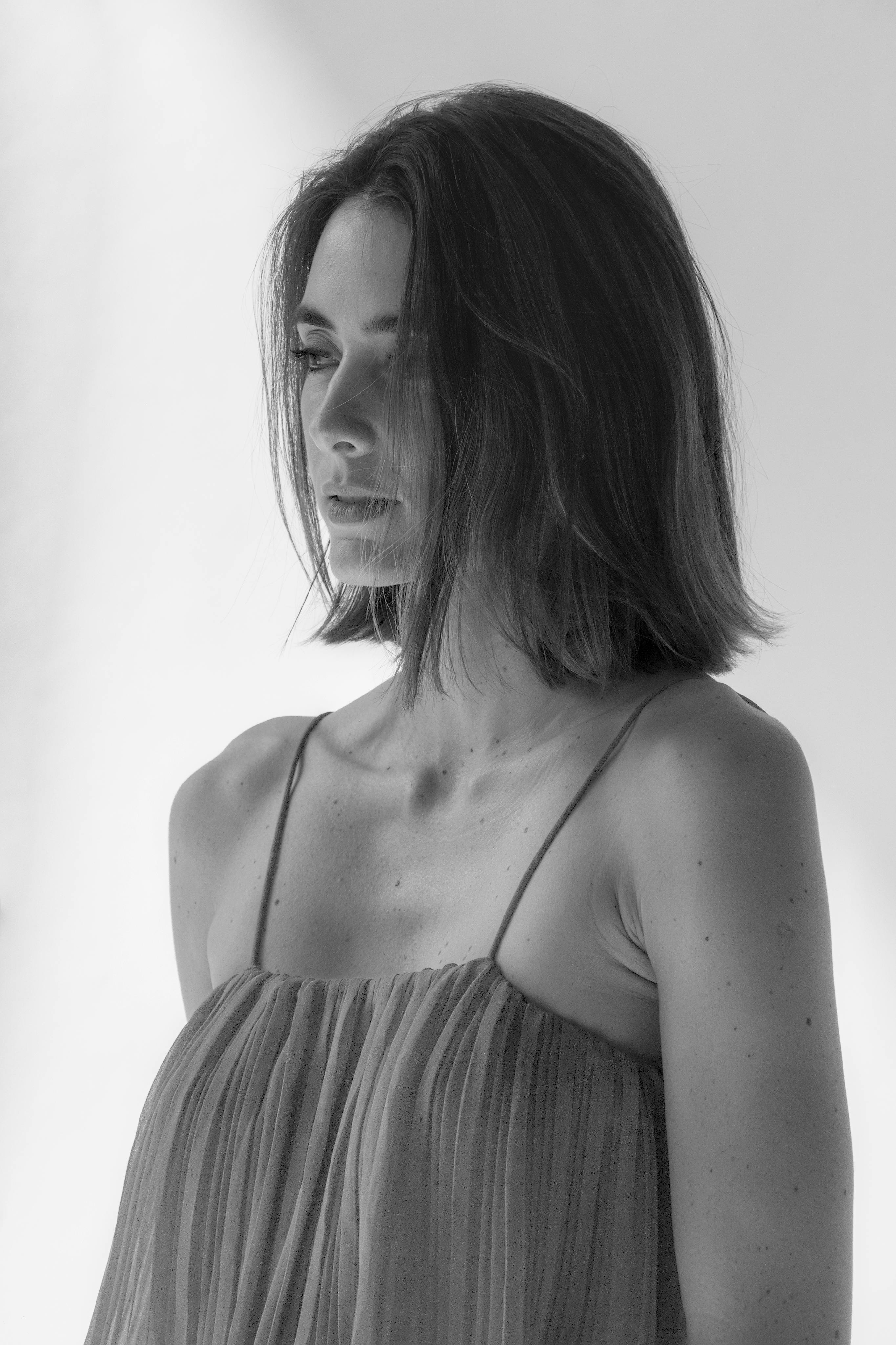 A sophisticated black and white portrait of a young woman with short hair in a studio setting.