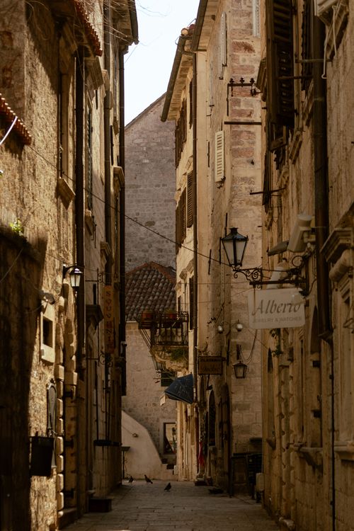 Free Explore the historic narrow street in Kotor with classic stone facades and warm sunlight. Stock Photo