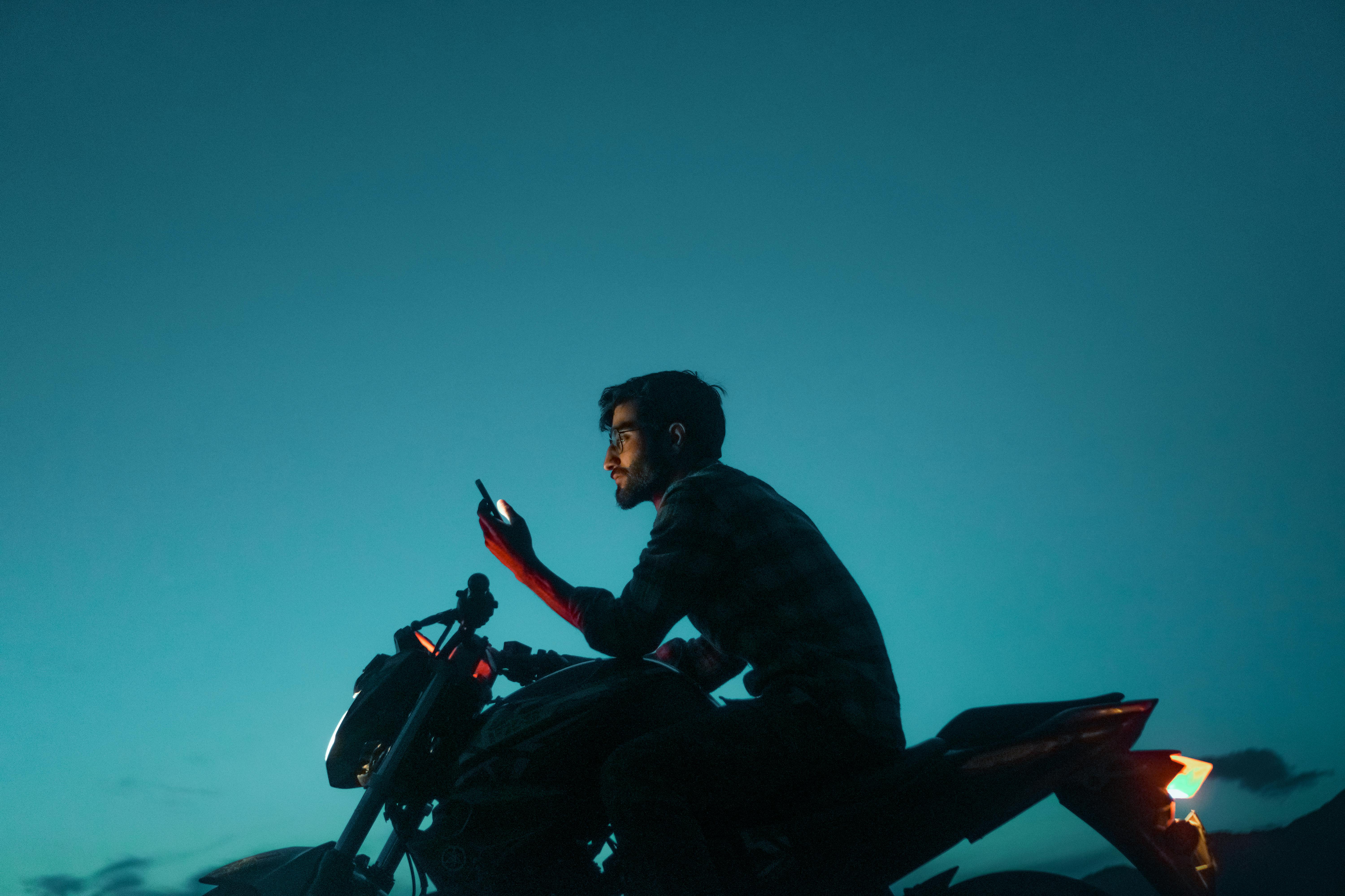 free photo of man on a motorcycle setting up navigation on the smartphone