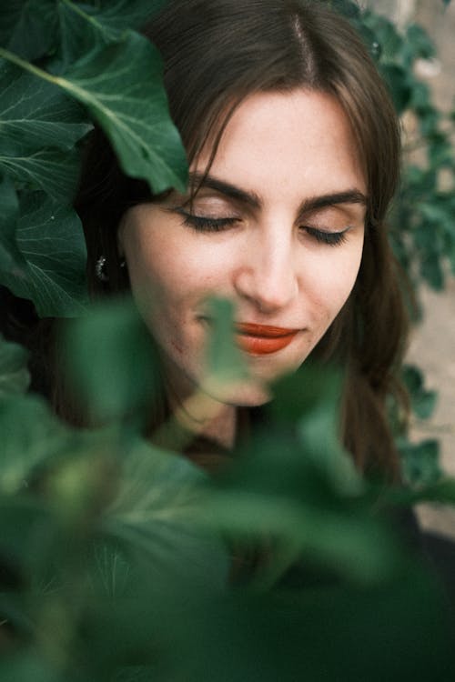 Woman with Eyes Closed behind Leaves