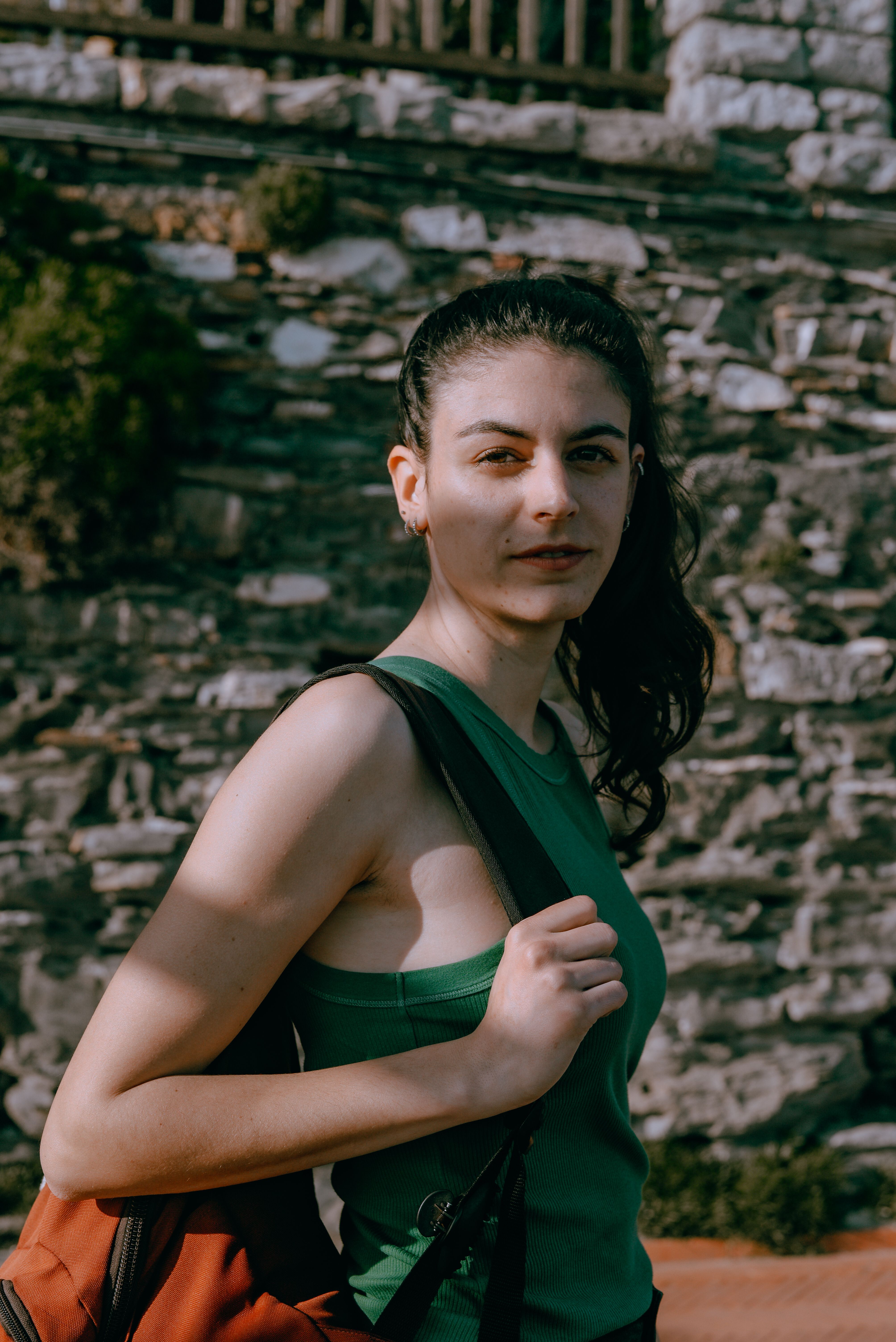 Young woman posing outdoors in Genoa, Italy with stone wall background.