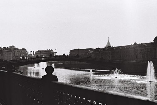 Free A serene urban river scene with a bridge and fountains in monochrome. Stock Photo