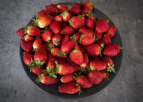 A tantalizing arrangement of fresh strawberries in a dark bowl on a textured background.
