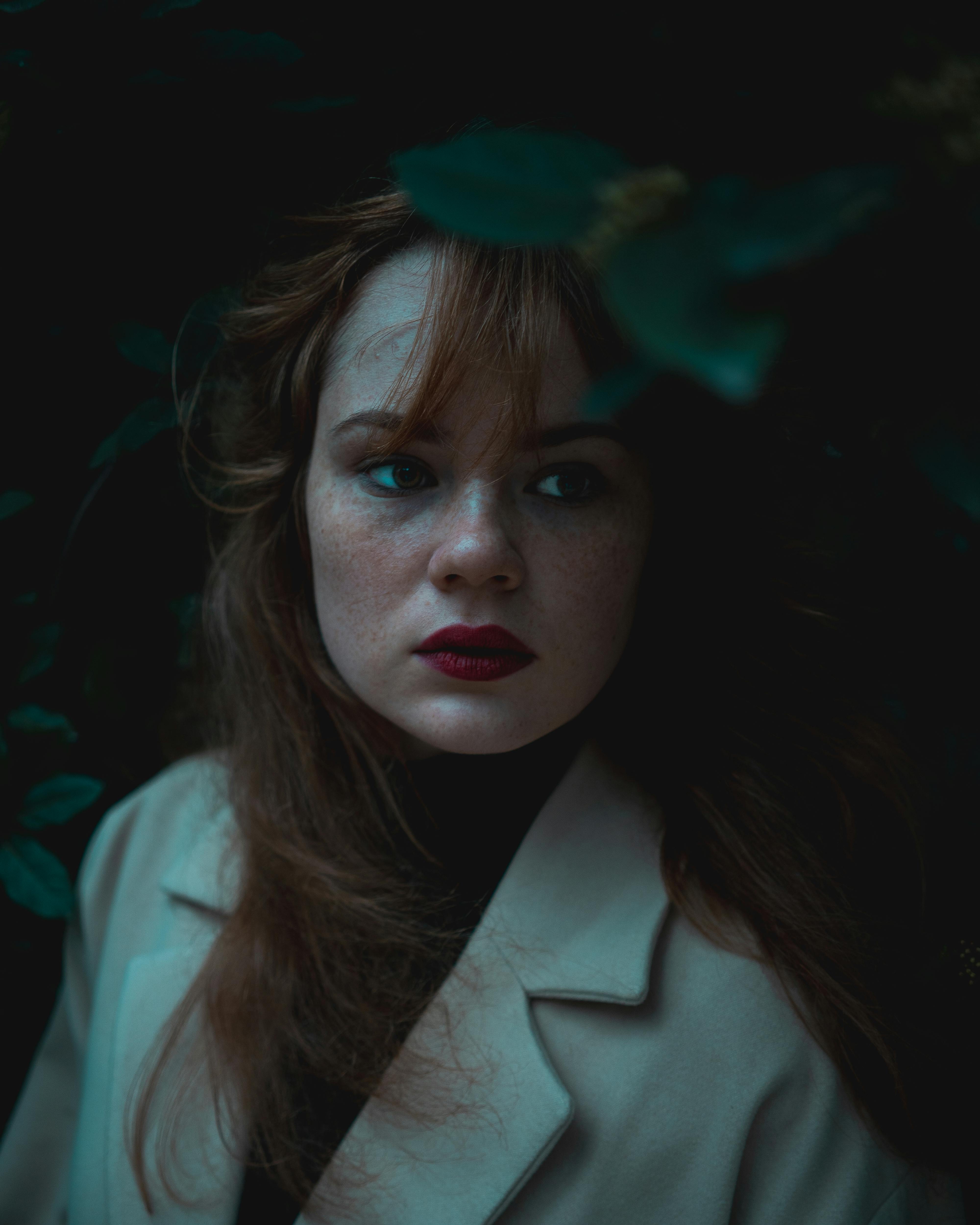 A captivating portrait of a woman with red lipstick in a moody, dark setting.