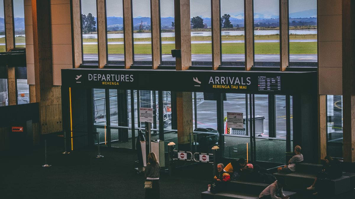 Busy airport terminal concourse with travelers and departure boards