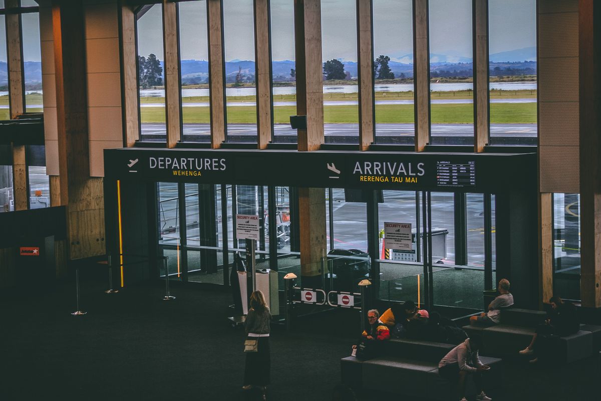 Modern international airport terminal with clear arrivals and departures signage — the kind of professional, well-organised arrivals environment where a GoEuroTaxi driver waits with your name sign