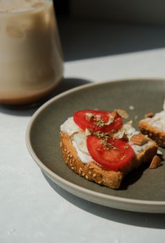 Savor a healthy breakfast with tomato and cheese on sesame toast, paired with iced coffee.