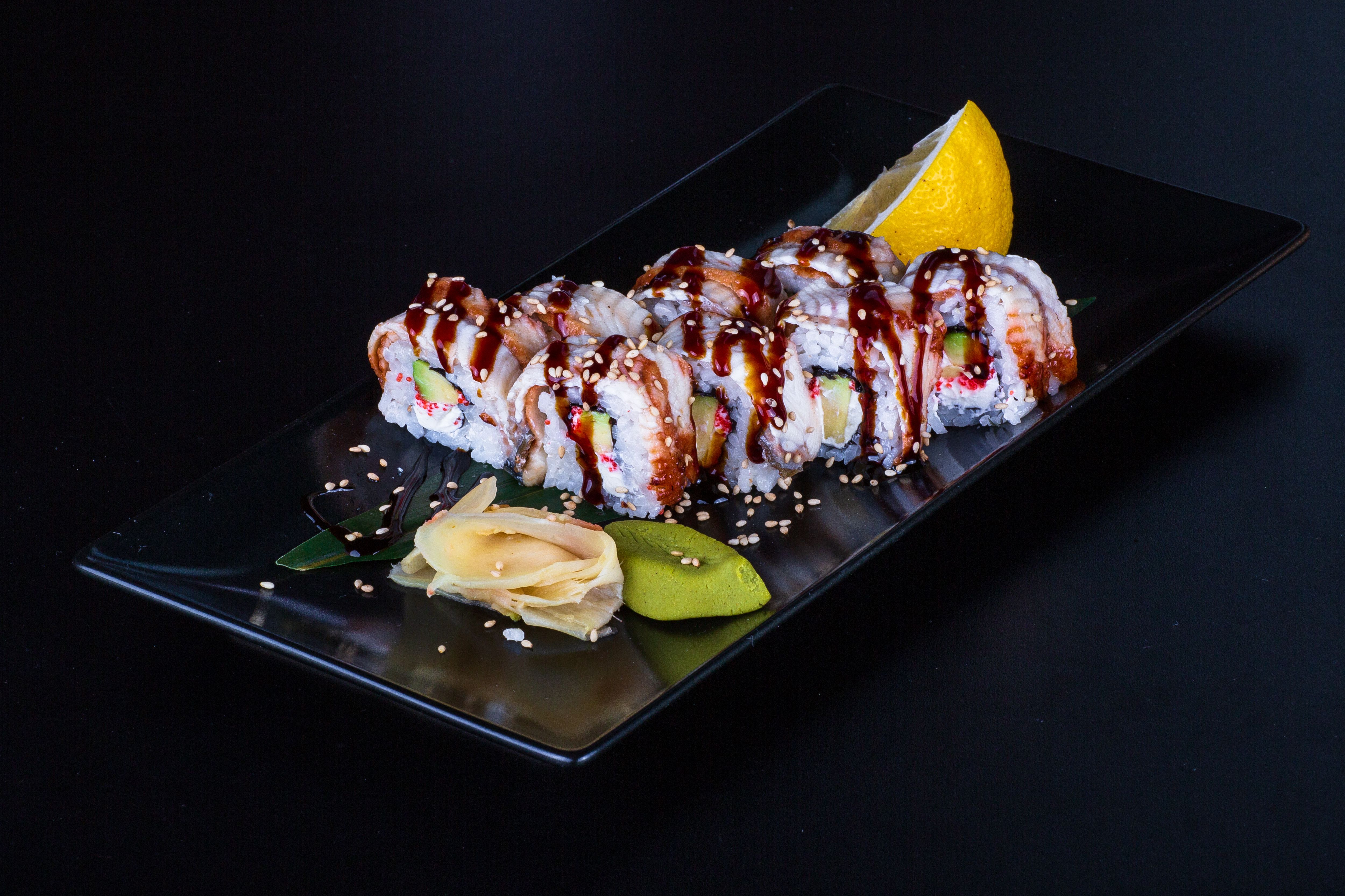 Delicious sushi rolls served with ginger and wasabi on a stylish black plate.