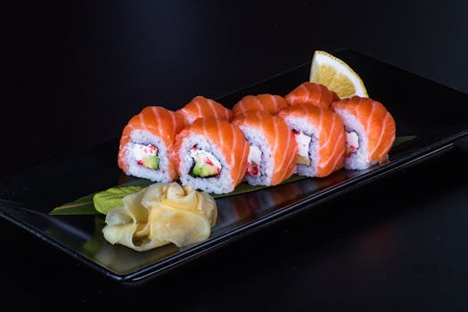 Close-up of salmon sushi rolls with ginger on a black plate, perfect for food photography.