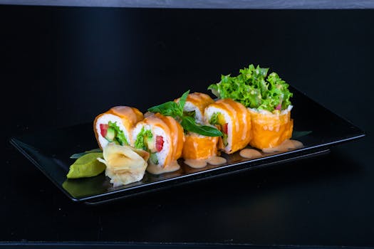 Delicious sushi rolls with salmon, vegetables, and a creamy sauce on a black plate.