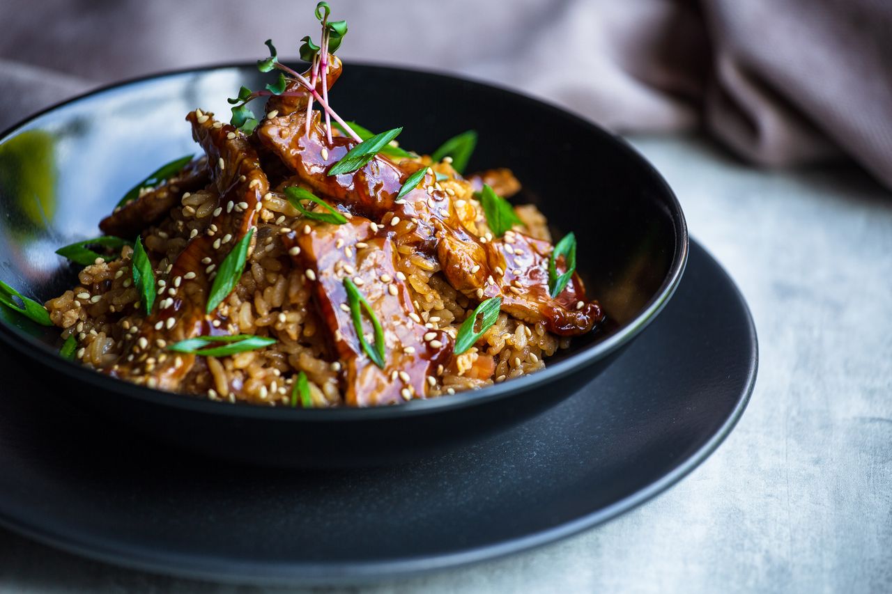 Teriyaki glazed beef and rice bowl with sesame seeds and fresh vegetables